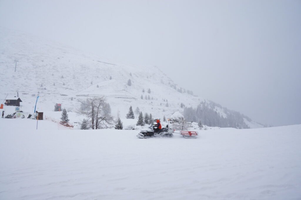 a misty day on a snowy mountainside, a snowmobile drives through the scene
